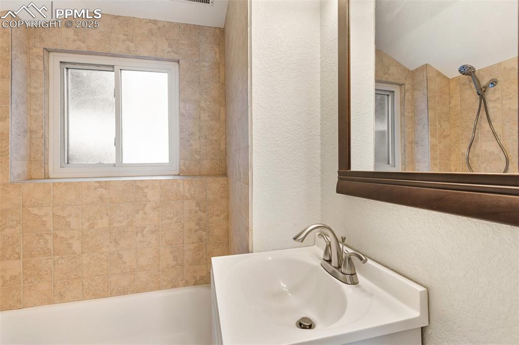 2518 Royalty Court Colorado Springs, CO 80904 - Photo 26 of 47 a bathroom with a sink a mirror and a window