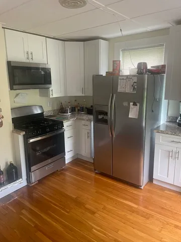 a kitchen with granite countertop a refrigerator and a stove top oven