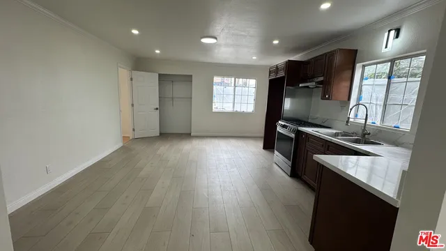 a view of a kitchen with kitchen island a sink wooden floor and a large window