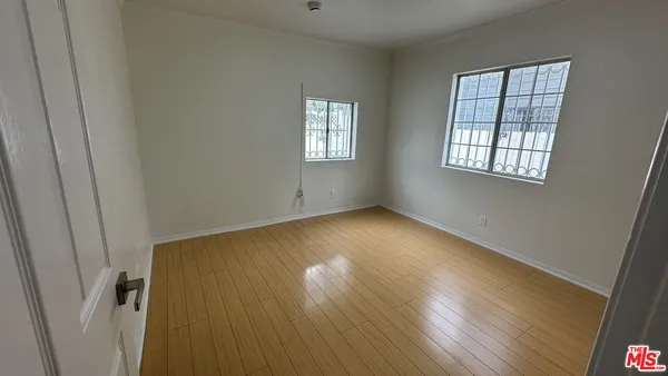a view of empty room with wooden floor and fan