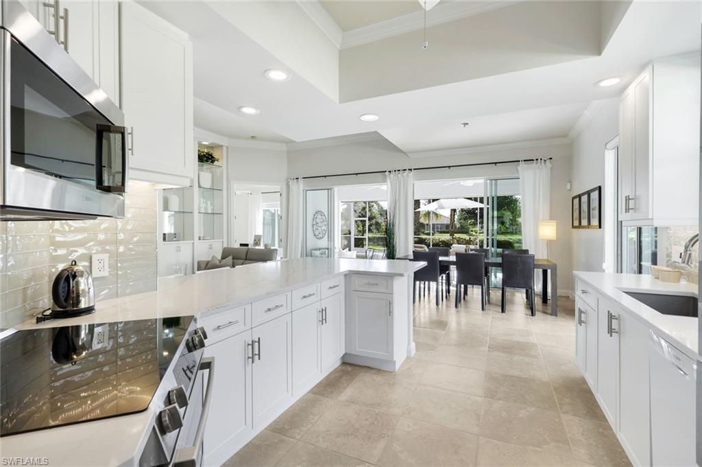 7063 Toscana Court Naples, FL 34114 - Photo 15 of 47 Kitchen with tasteful backsplash, ornamental molding, appliances with stainless steel finishes, a peninsula, and white cabinets