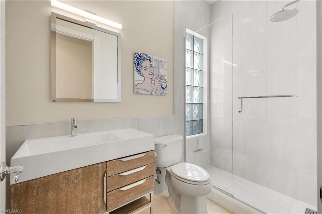 7063 Toscana Court Naples, FL 34114 - Photo 26 of 47 Bathroom with vanity, a stall shower, tile walls, and a wainscoted wall