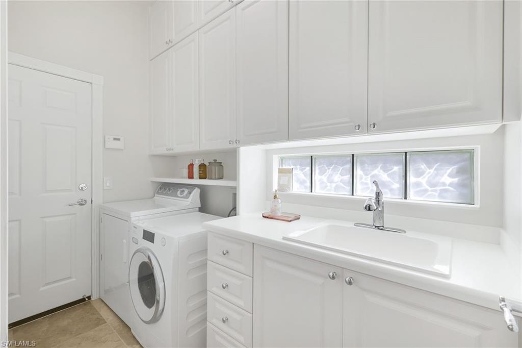 7063 Toscana Court Naples, FL 34114 - Photo 30 of 47 Laundry area with washer and dryer and cabinet space