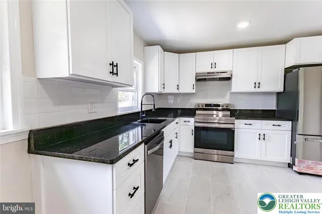 a kitchen with granite countertop white cabinets and stainless steel appliances