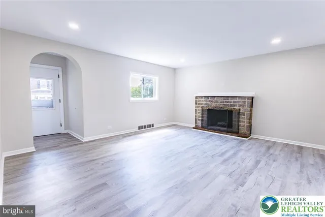 an empty room with wooden floor and a fireplace