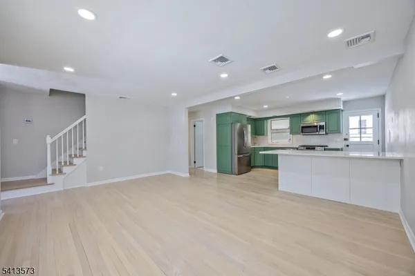 a view of large kitchen with kitchen island a sink wooden floor and a refrigerator