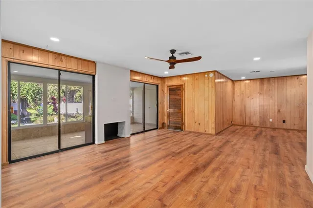 a view of empty room with wooden floor and fan