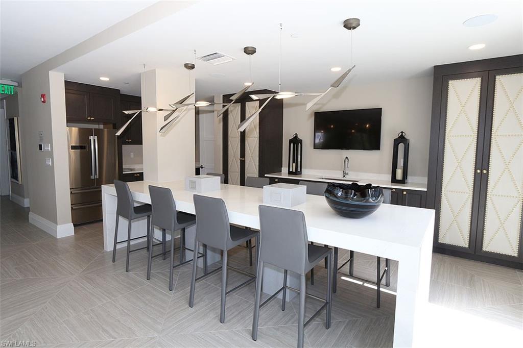 1135 3rd Avenue South, Unit 517 Naples, FL 34102 - Photo 31 of 35 a kitchen with stainless steel appliances kitchen island granite countertop a table and chairs