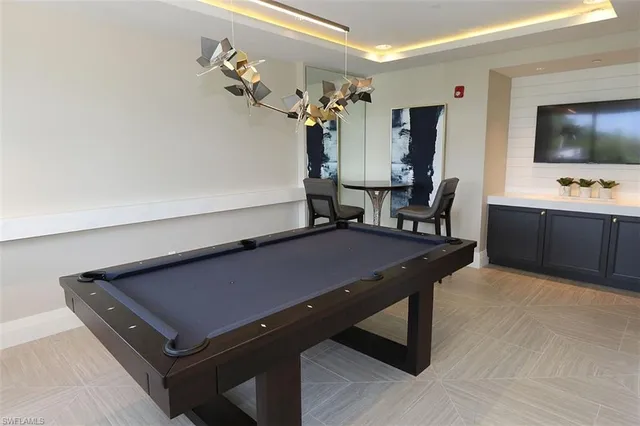 a room with furniture pool table flat screen tv and windows
