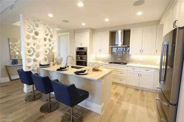 a kitchen with stainless steel appliances kitchen island granite countertop a sink stove and refrigerator