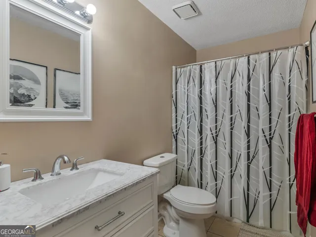 a bathroom with a granite countertop sink and a toilet