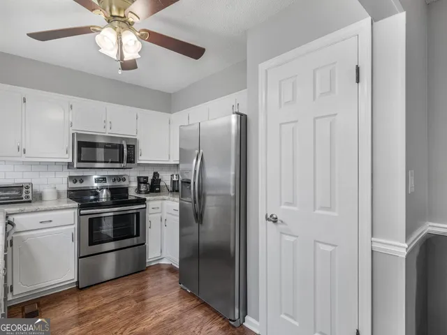 a kitchen with stainless steel appliances granite countertop white cabinets and a refrigerator