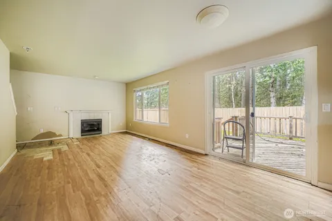 an empty room with wooden floor fireplace and windows