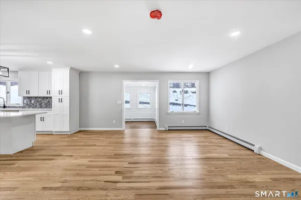 a view of an empty room with window and wooden floor
