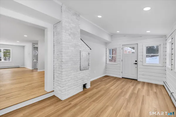 a view of an empty room with wooden floor and a window