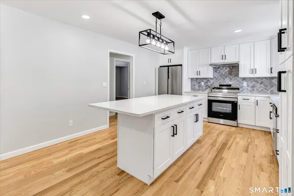 a kitchen with stainless steel appliances white cabinets and wooden floor