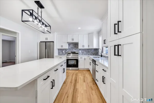 a large kitchen with stainless steel appliances granite countertop a lot of counter space and wooden floors