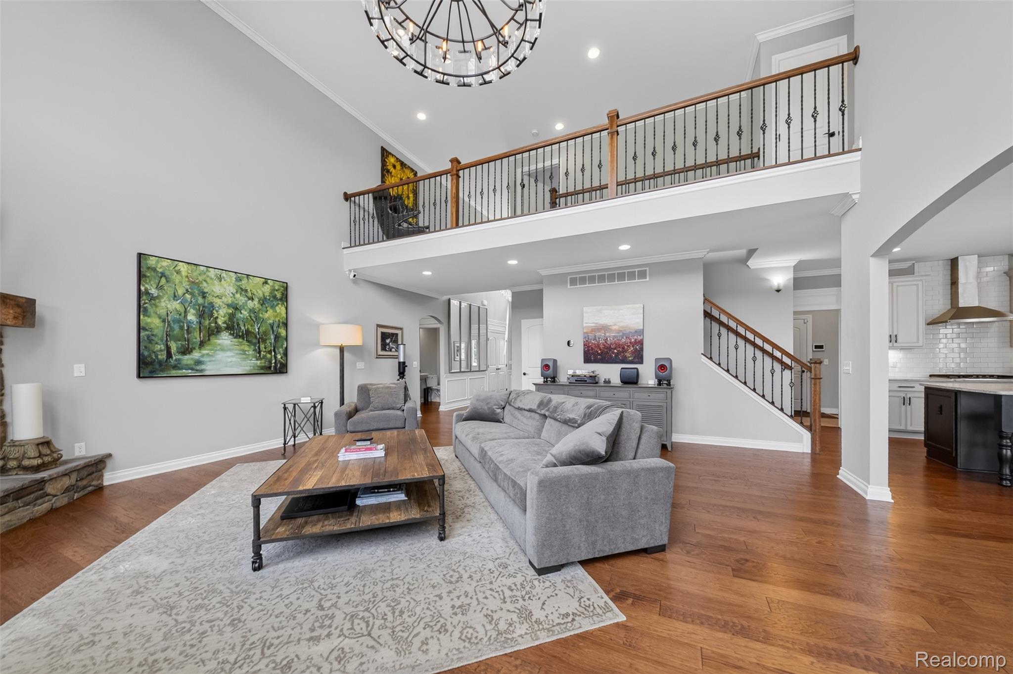 2531 Walnut View Drive Howell, MI 48855 - Photo 11 of 34 Spacious living area featuring a two-story ceiling, a stone-clad fireplace, and hardwood flooring