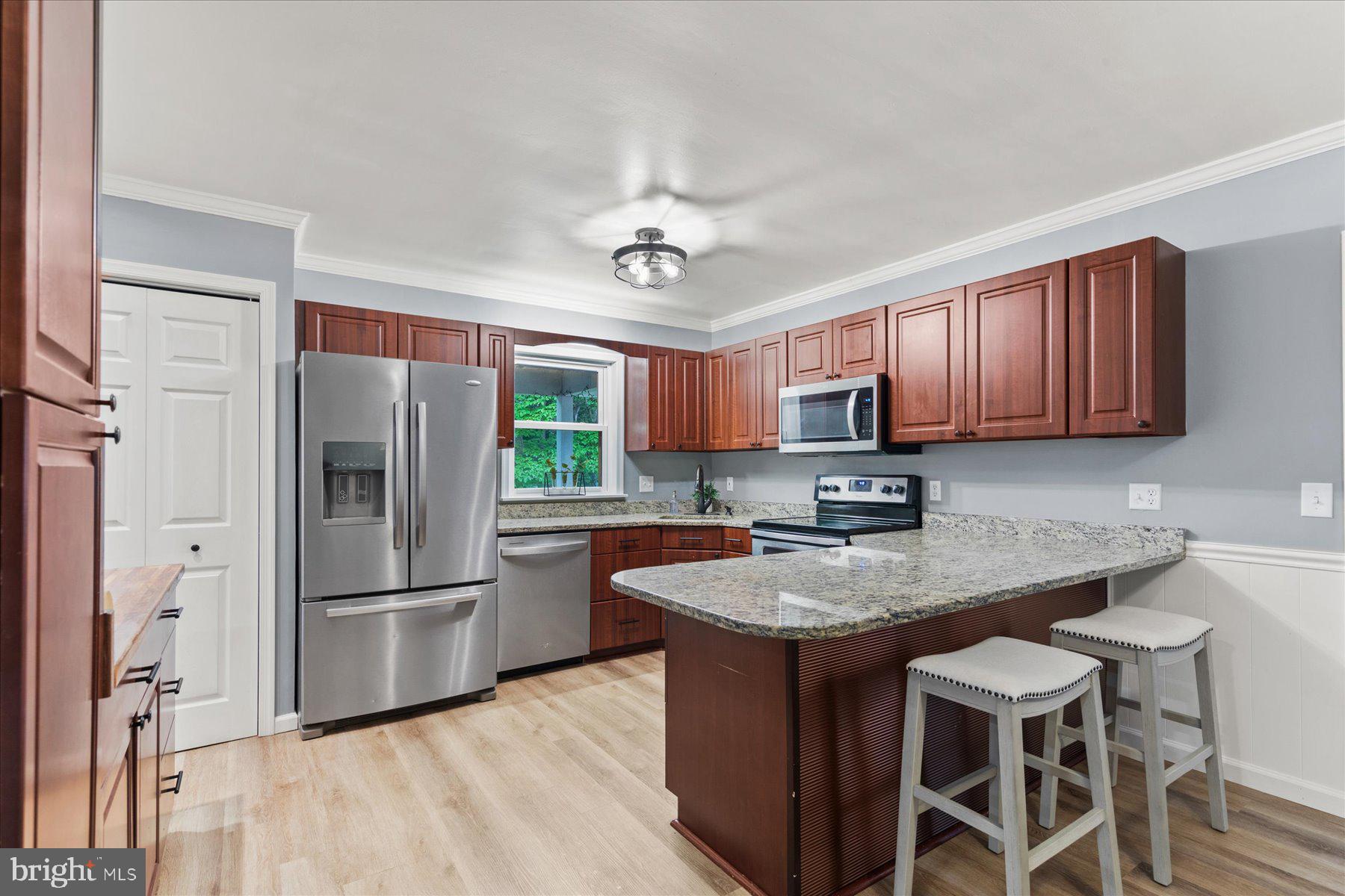 4 Poacher Berlin, MD 21811 - Photo 10 of 45 a kitchen with granite countertop stainless steel appliances a refrigerator a stove a sink dishwasher a dining table and chairs with wooden floor