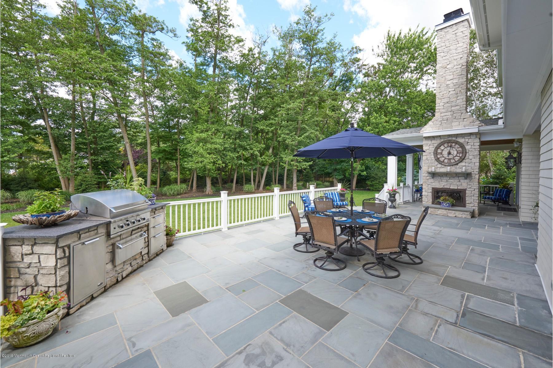 8 Heathcliff Road Rumson, NJ 07760 - Photo 40 of 46 a view of a patio with table and chairs under an umbrella with a barbeque