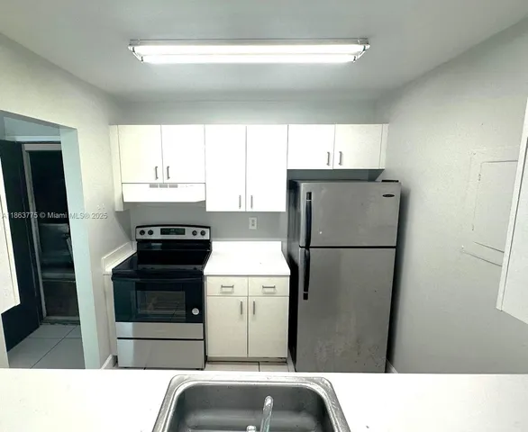 a kitchen with a refrigerator sink stove and cabinets