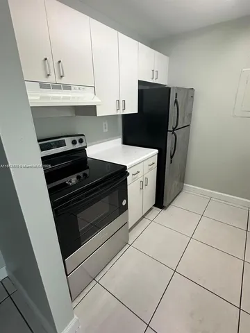 a kitchen with granite countertop a refrigerator and a stove top oven