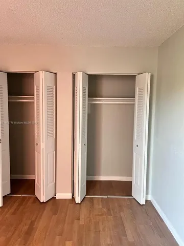 an empty room with wooden floor closet and windows