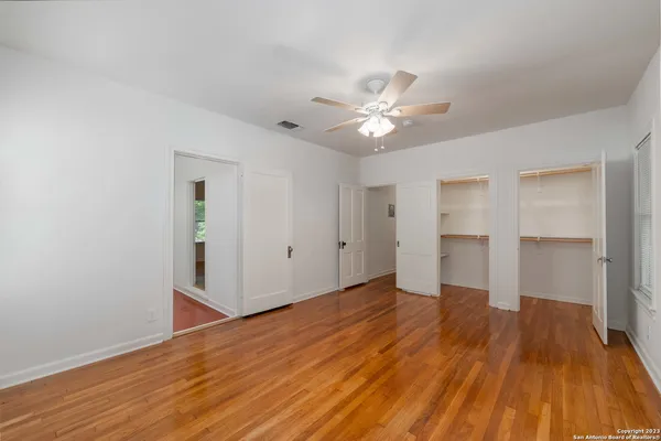 a view of empty room with wooden floor and fan