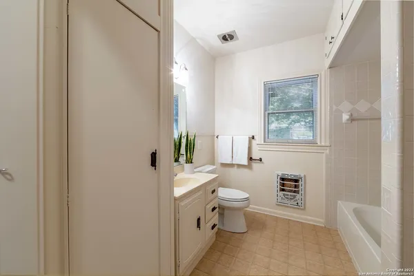 a bathroom with a toilet sink a mirror a window and shower
