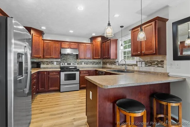 a kitchen with stainless steel appliances granite countertop a stove a sink dishwasher a microwave oven and a refrigerator with wooden cabinets