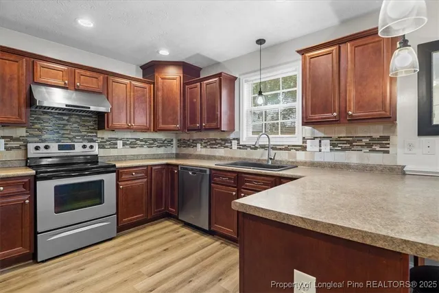 a kitchen with stainless steel appliances granite countertop wooden cabinets stove top oven and sink