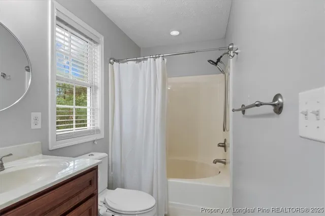 a bathroom with a granite countertop bathtub shower sink vanity and toilet