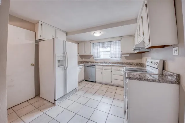 a kitchen with white cabinets stainless steel appliances and a window