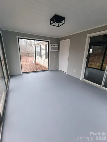 a view of an empty room with a window and a kitchen