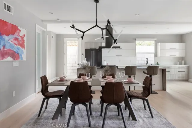 a view of dining room and livingroom with furniture wooden floor a rug a painting and a chandelier
