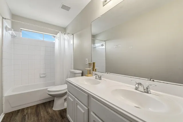 a bathroom with a bathtub shower sink mirror and toilet