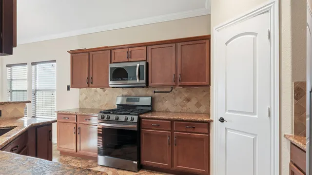 a kitchen with kitchen island granite countertop stainless steel appliances stove microwave and sink