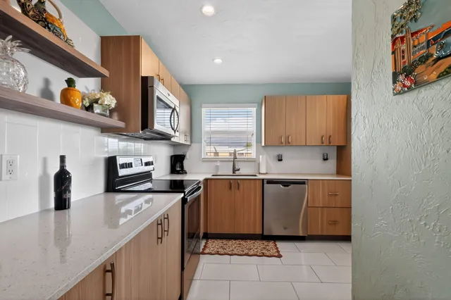 a kitchen with stainless steel appliances a sink a stove a microwave a refrigerator and cabinets