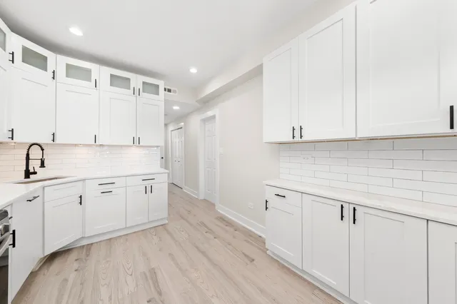 a kitchen with stainless steel appliances white cabinets a sink a stove a refrigerator and white cabinets