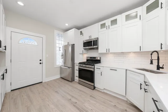 an empty room with wooden floor cabinet and windows