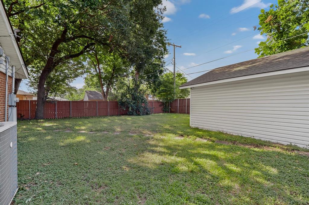 405 Easton Road Dallas, TX 75218 - Photo 32 of 36 Expansive fenced yard with mature trees and a detached garage featuring white siding