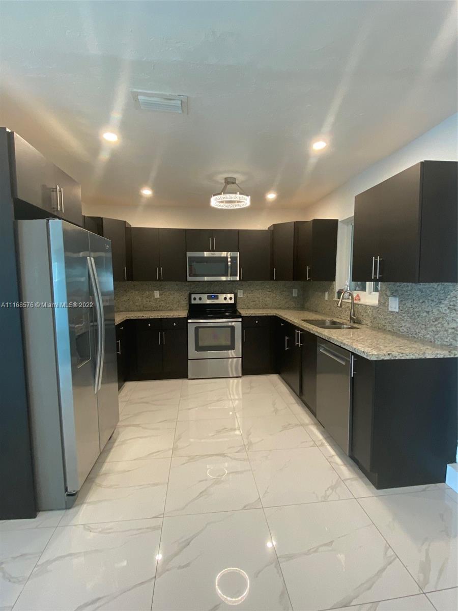 6561 Southwest 30th Street, Unit FRONT Miami, FL 33155 - Photo 14 of 18 a large kitchen with a large counter top stainless steel appliances and cabinets