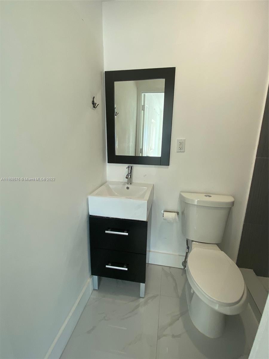 6561 Southwest 30th Street, Unit FRONT Miami, FL 33155 - Photo 3 of 18 a bathroom with a toilet sink and mirror