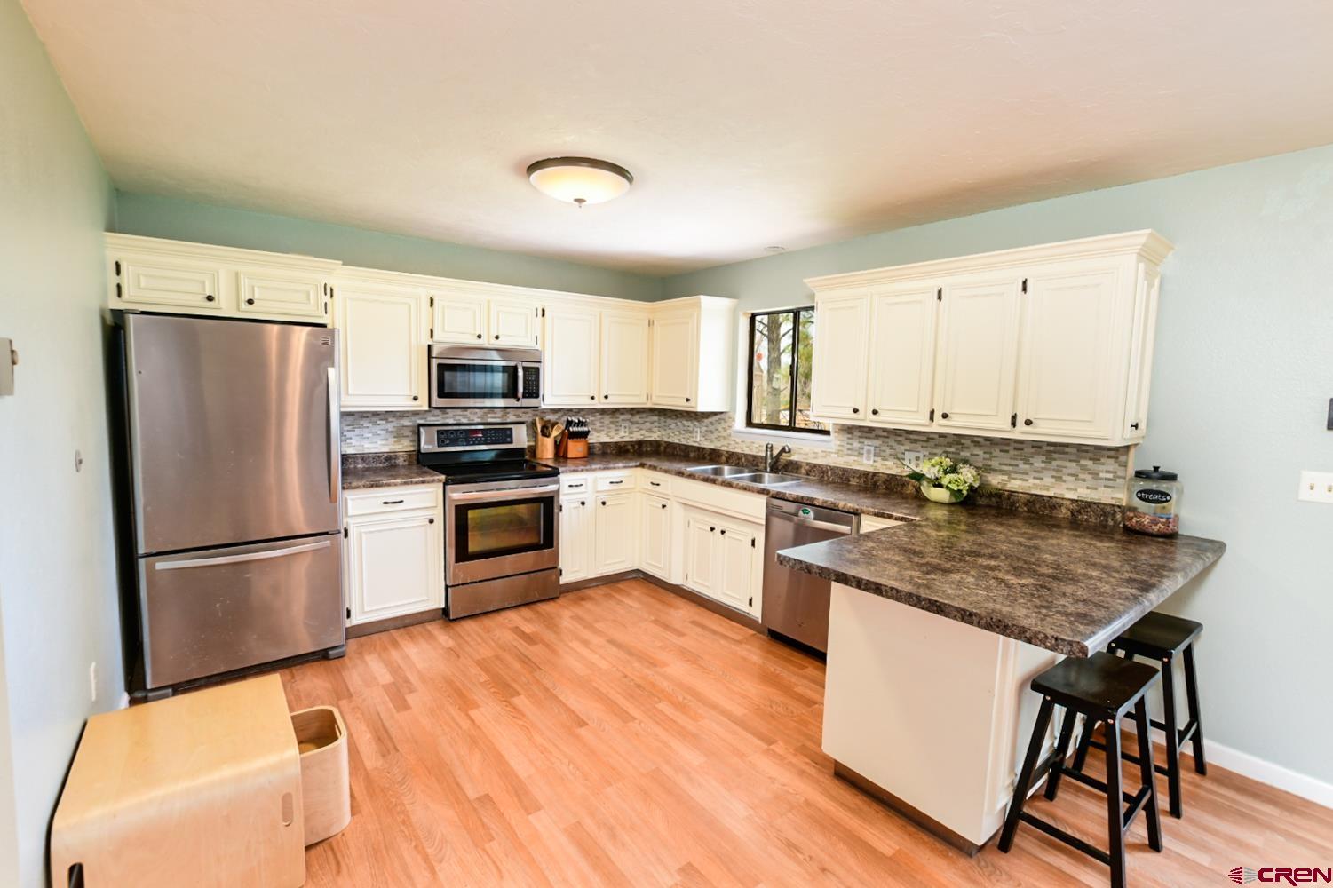 22247 H75 Road Delta, CO 81416 - Photo 14 of 35 a kitchen with granite countertop a refrigerator a stove a sink dishwasher and white cabinets with wooden floor
