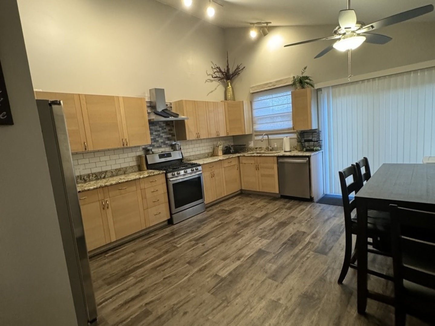 4050 Ridge Road Zion, IL 60099 - Photo 2 of 10 a kitchen with stainless steel appliances granite countertop a stove top oven a sink dishwasher a dining table and chairs with wooden floor