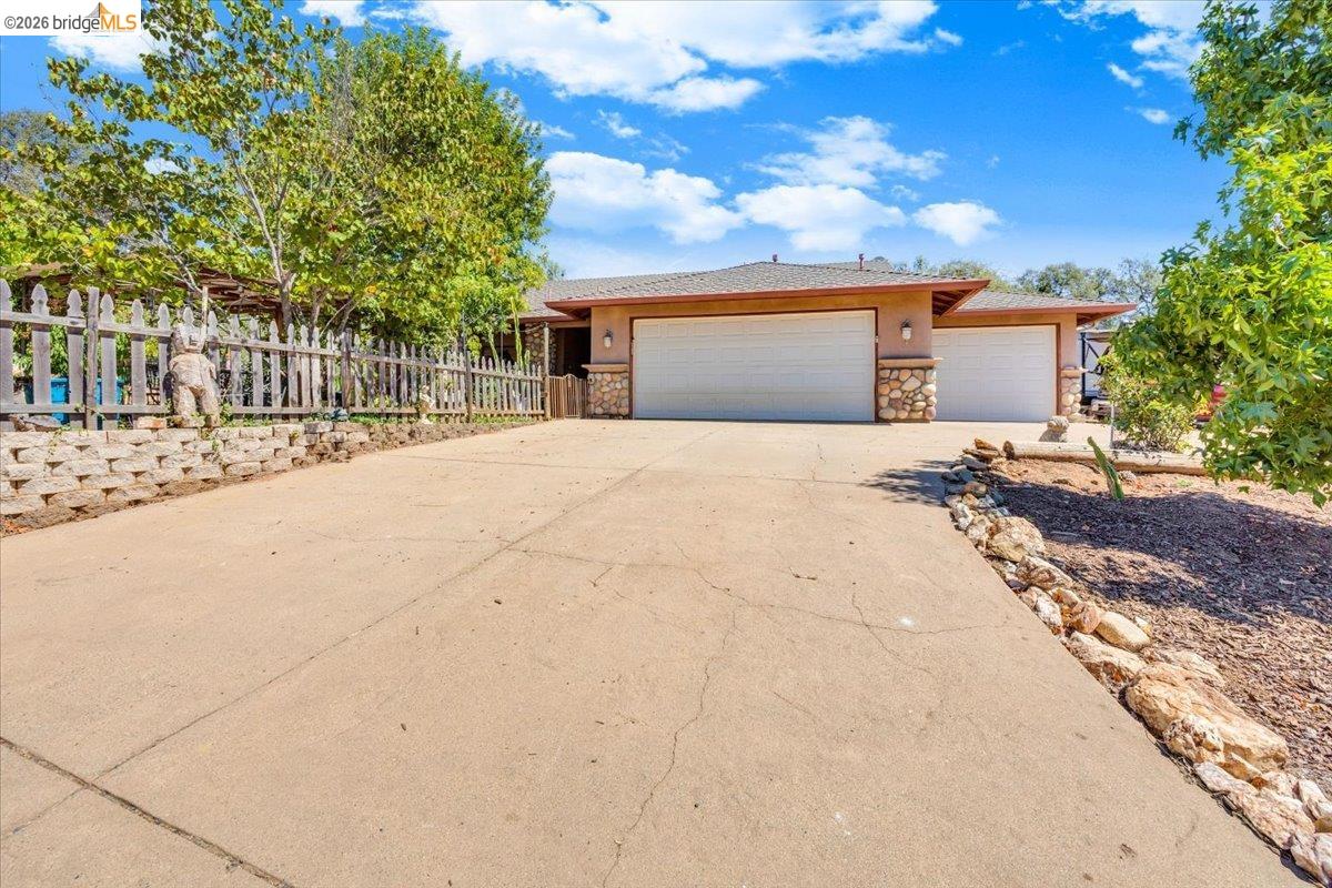 Two-car garage, stone facade accents, stucco exterior, sloped roof, and a concrete driveway