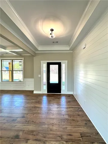 an empty room with wooden floor chandelier and windows