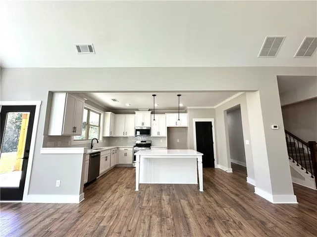a living room with stainless steel appliances furniture a refrigerator and wooden floor