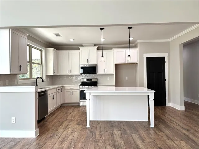 a kitchen with kitchen island a white counter top space a sink a stove and refrigerator