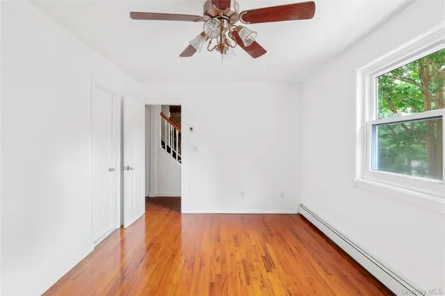 a view of a room with wooden floor ceiling fan and window